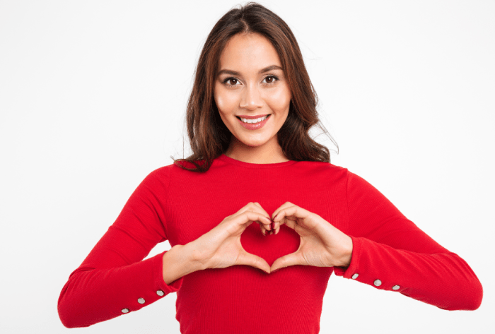 Woman with red shirt holding her hands to form a heart.