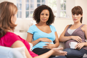 Photo of three pregnant women sitting conversing