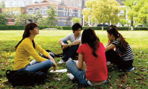 Photo of four students sitting outside talking