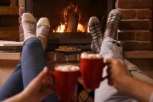 two people sitting by fire with hot chocolate