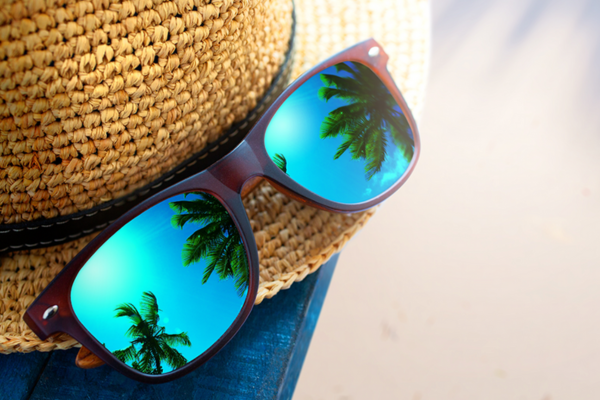 Reflective sunglasses on a beach hat show palm trees and sky